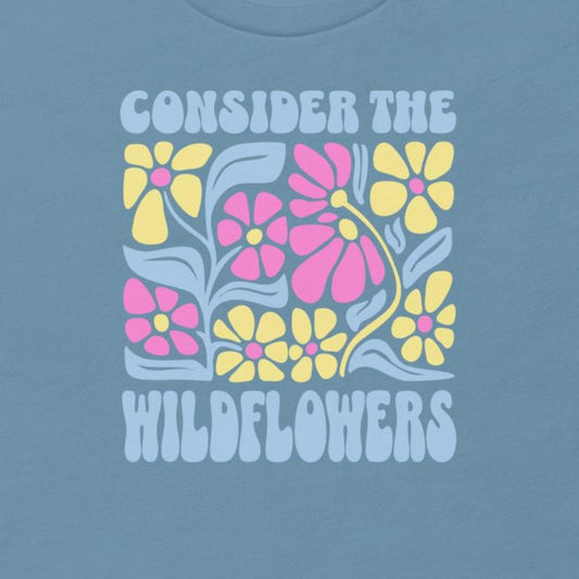T-shirt with floral design and text 'Consider the Wildflowers' on a blue background