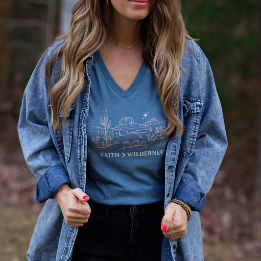 Person wearing a blue denim jacket over a blue t-shirt with a graphic design and text, standing outdoors.