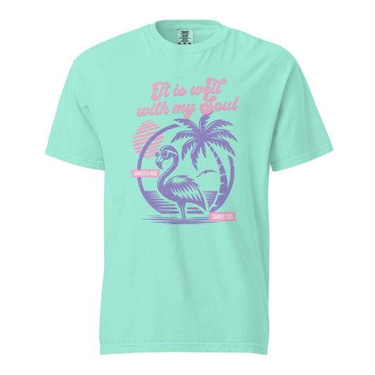 Mint green “It Is Well” Christian t-shirt featuring retro flamingo, palm trees, and beach sunset design in pink and purple tones.