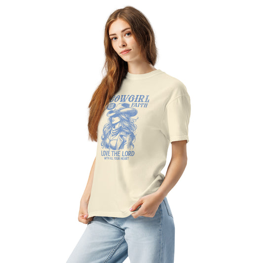 Lady wearing ivory colored Cowgirl Faith t-shirt featuring a graphic image of a cowgirl wearing a hat and subtext of Love the Lord with all your heart.