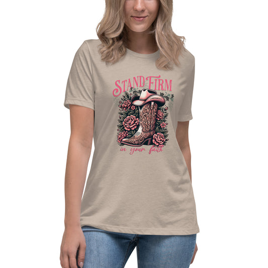 Model wearing a heather stone T-shirt featuring a decorative graphic of a cowboy boot filled with flowers and the phrase 'Stand Firm in Your Faith'; 1 Corinthians 16:13 is inscribed on the bill of a hat within the design