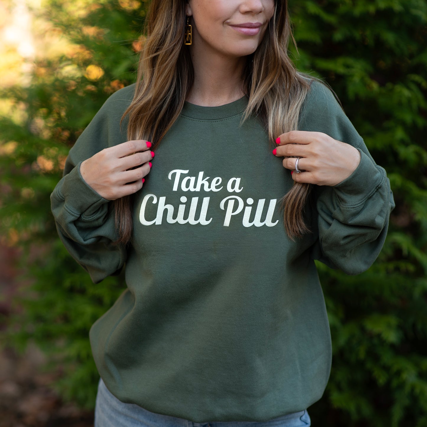 Female model wearing green sweatshirt with 'Take a Chill Pill' text in white