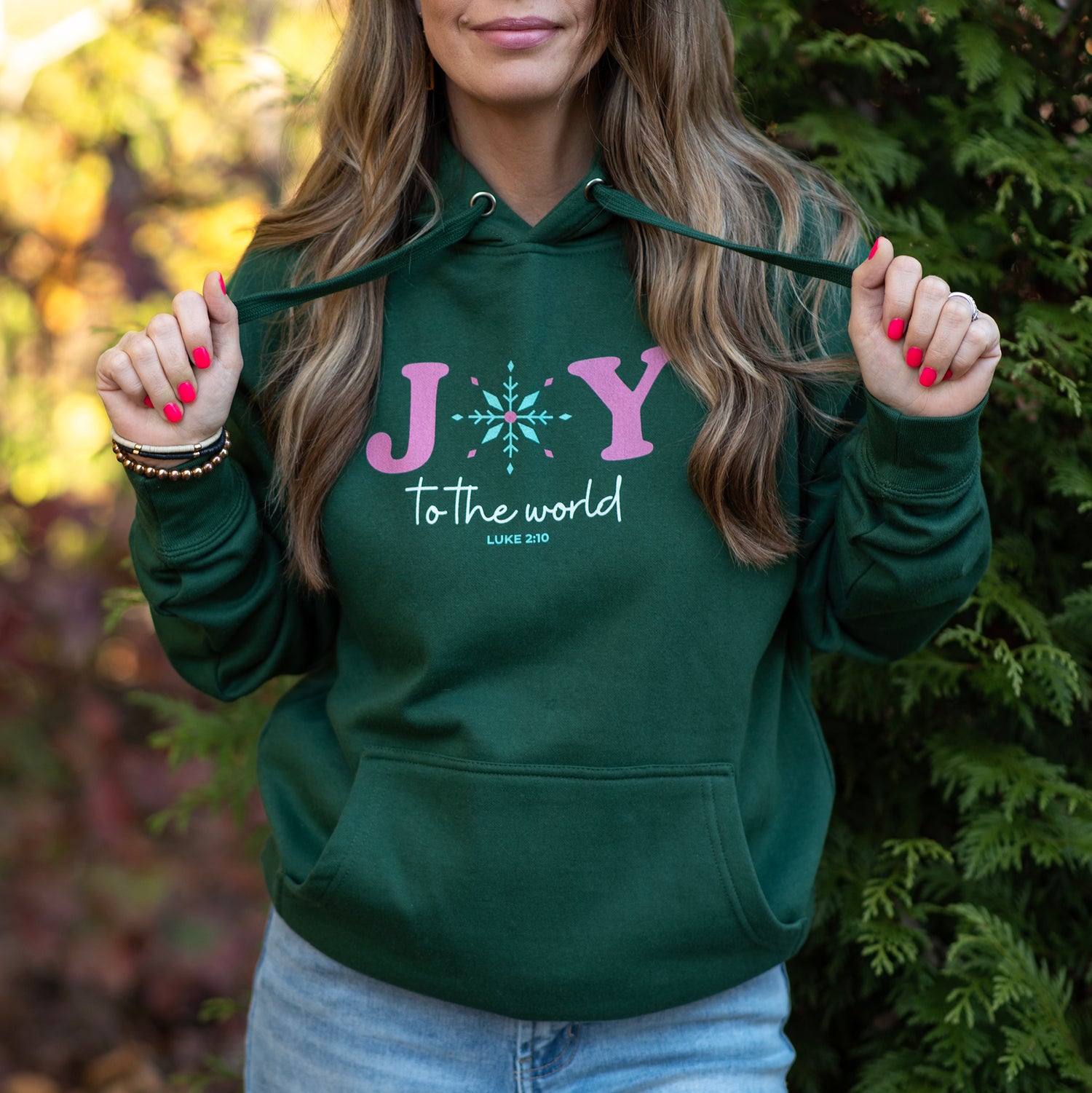 Person wearing a green hoodie with 'Joy to the world' text, standing outdoors.