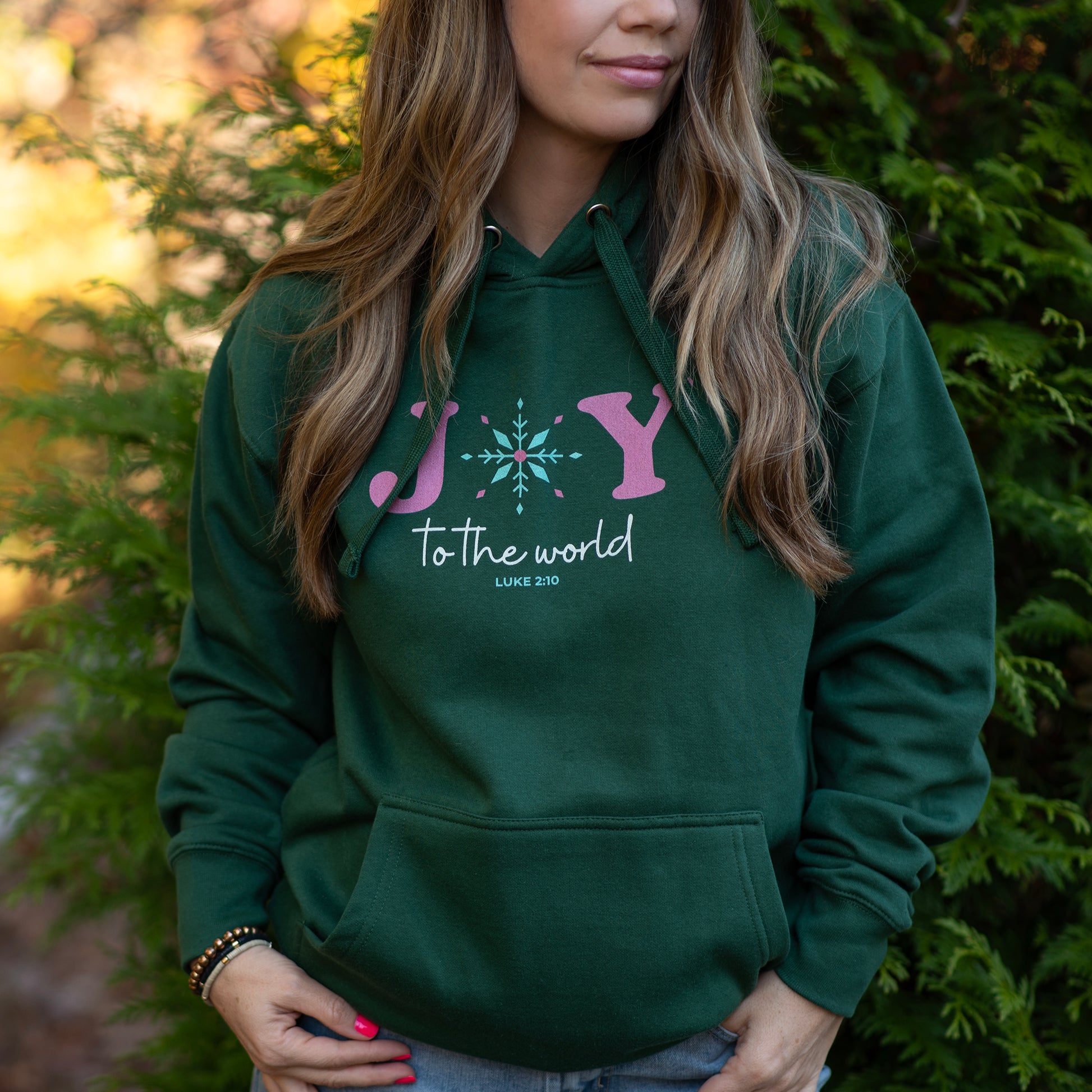 Person wearing a green hoodie with a pink and white design, standing outdoors.