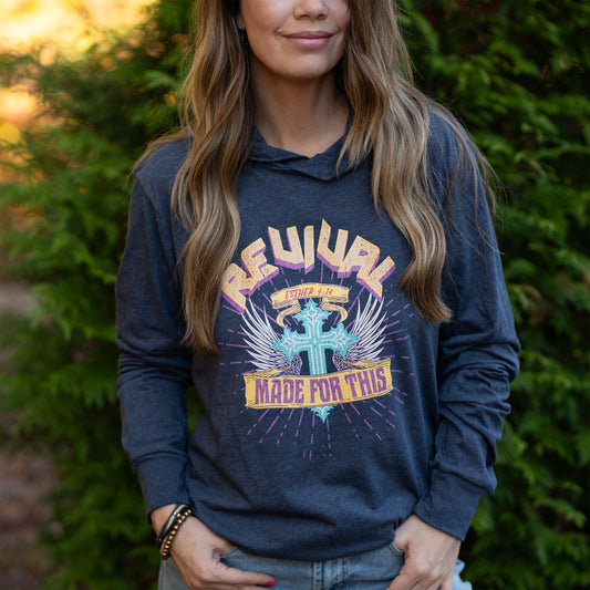 Model wearing heather navy long sleeved hooded t-shirt with 'Revival Made for This' graphic design featuring a cross and wings.