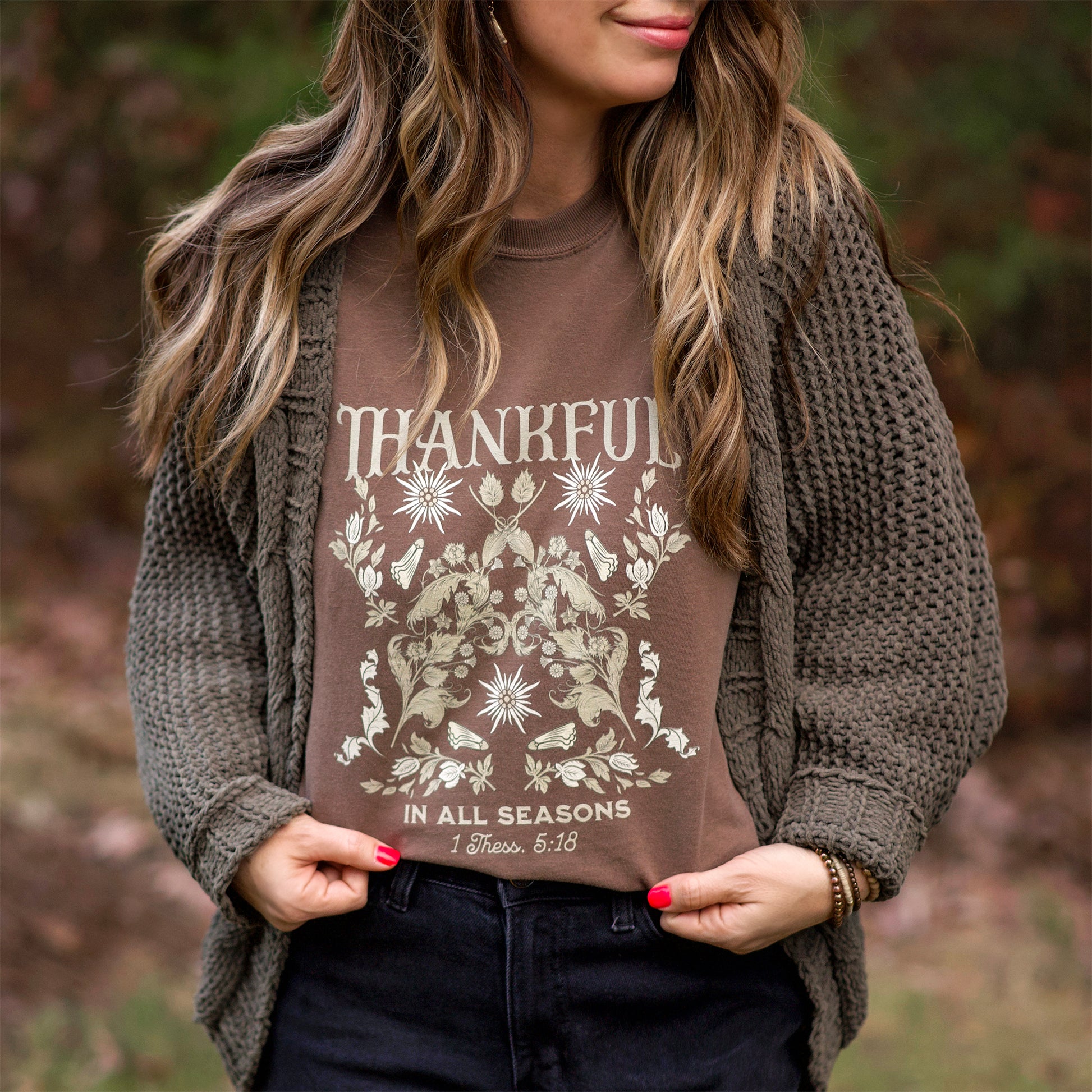 Woman wearing a brown 'Thankful in All Seasons' shirt outdoors