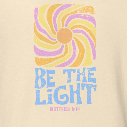 Beige t-shirt with colorful sun design and 'Be the Light' text on a beige background