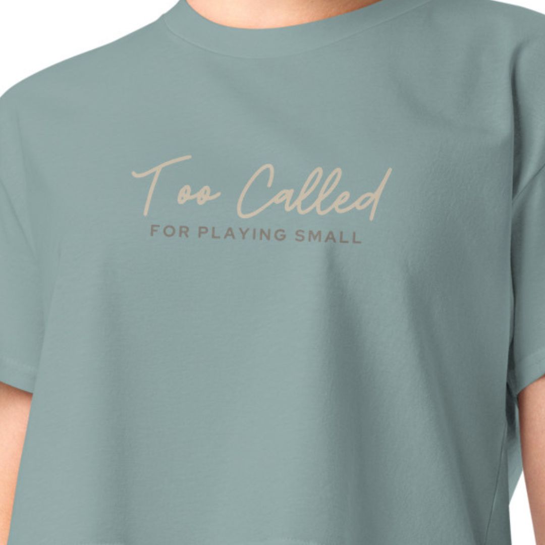 Upclose shot of t-shirt image on model. Text reads too called for playing small