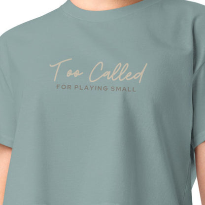 Upclose shot of t-shirt image on model. Text reads too called for playing small