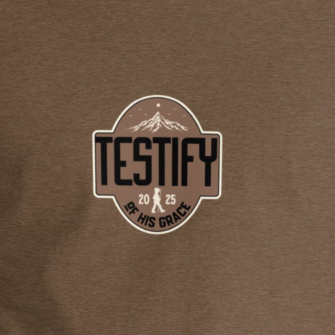 Brown shirt with Testify of His Grace text with a mountain in the background. 