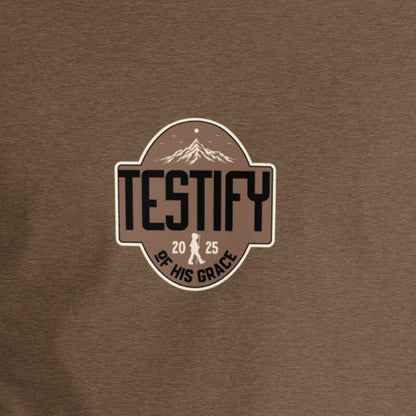 Brown shirt with Testify of His Grace text with a mountain in the background. 