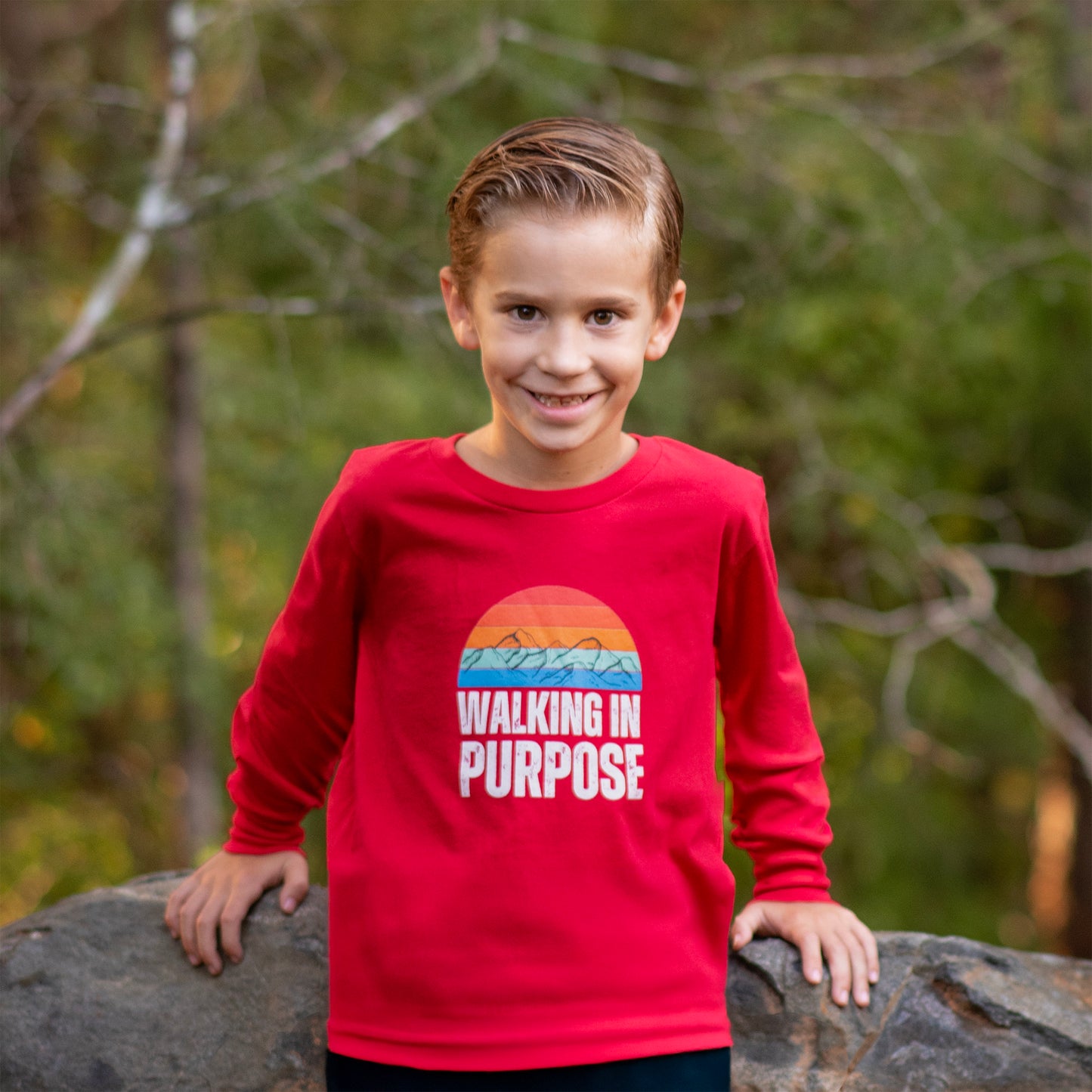 Child wearing a red shirt with 'Walking in Purpose' text, standing outdoors.