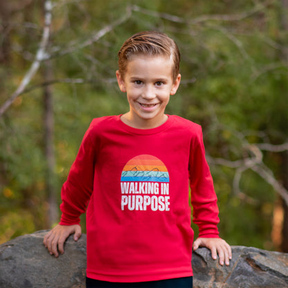 Child wearing a red shirt with 'Walking in Purpose' text, standing outdoors.