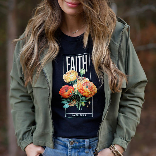 Person wearing a black t-shirt with floral design and 'FAITH OVER FEAR' text, paired with an olive green jacket.