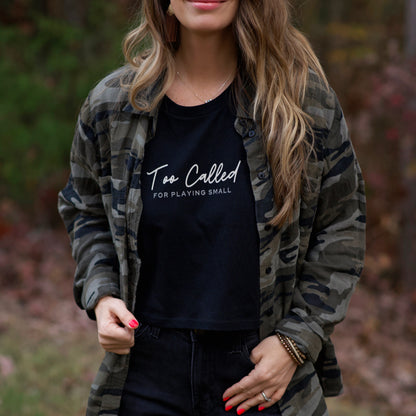 Woman wearing a black t-shirt with text and a camouflage jacket outdoors