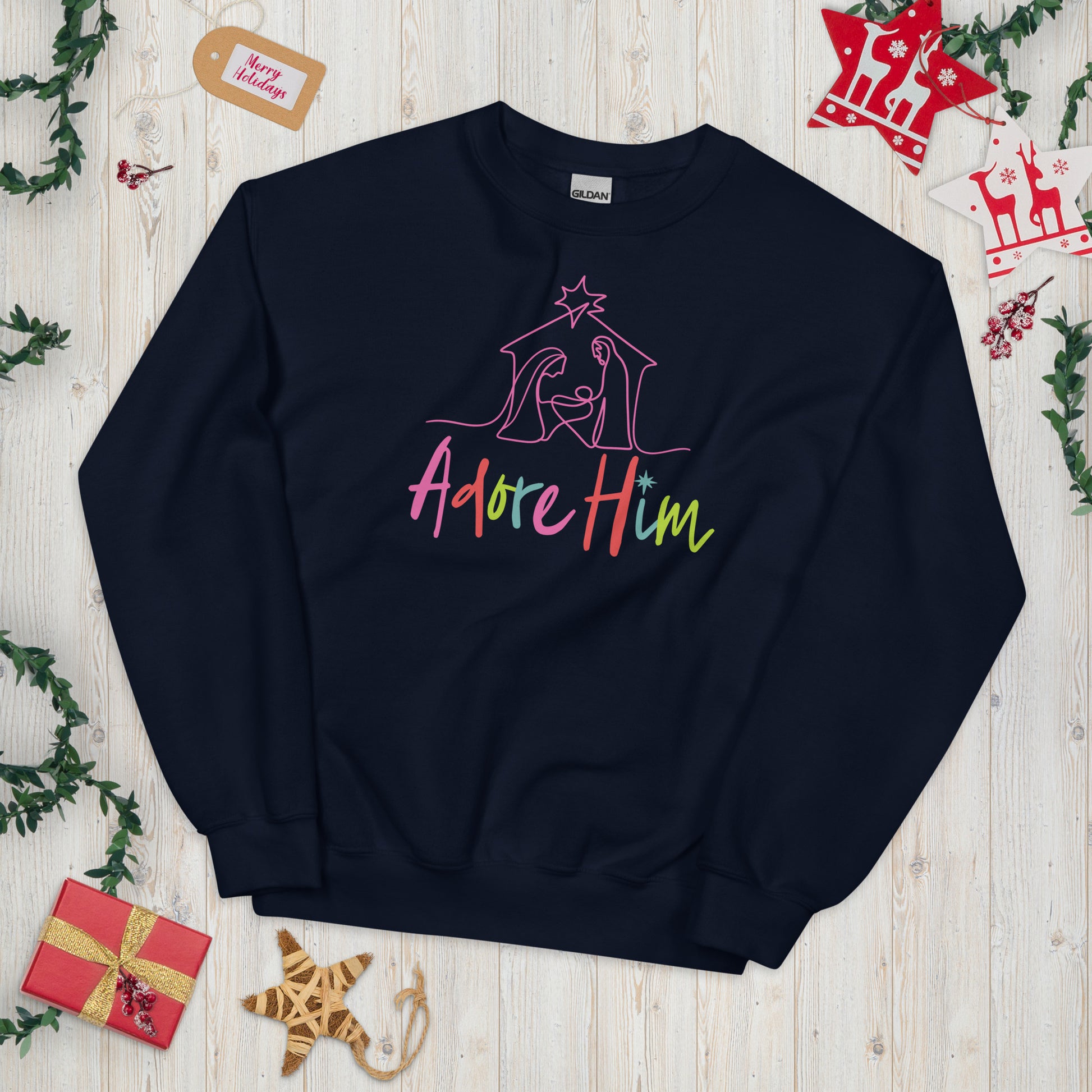 Navy colored Christian Christmas sweatshirt featuring colorful silhouette of a nativity scene with Adore Him text. 