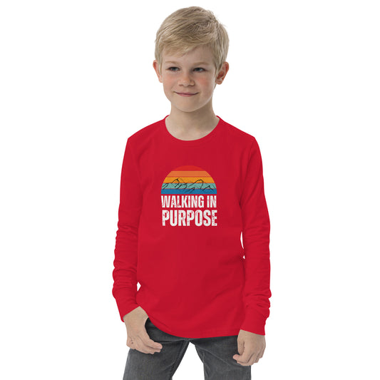 A boy wearing a long sleeved red t-shirt with the words Walking In Purpose and a colorful mountain range
