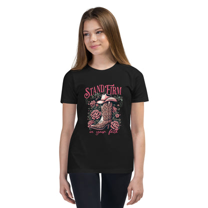 Girl wearing black graphic tee with cowboy boot, flowers, and 'Stand Firm in Your Faith' text. 1 Corinthians 16:13 inscribed on bill of cowboy hat.